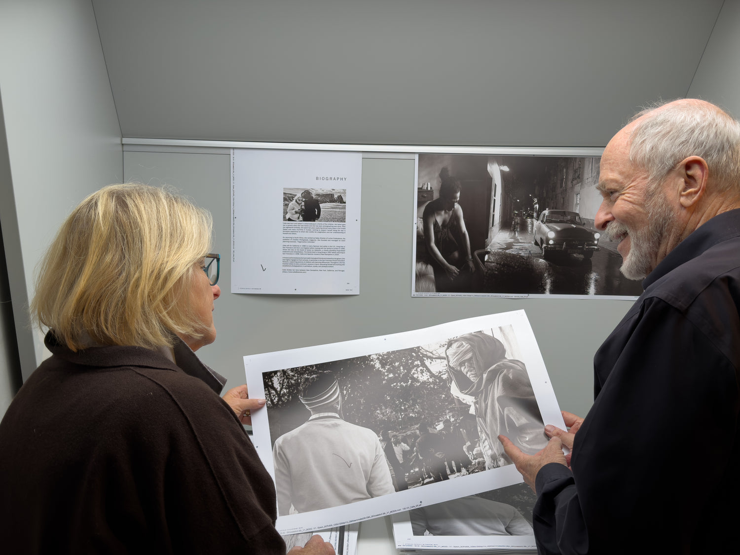 Calla and a man looking at a framed black and white photograph in an exhibition setting.